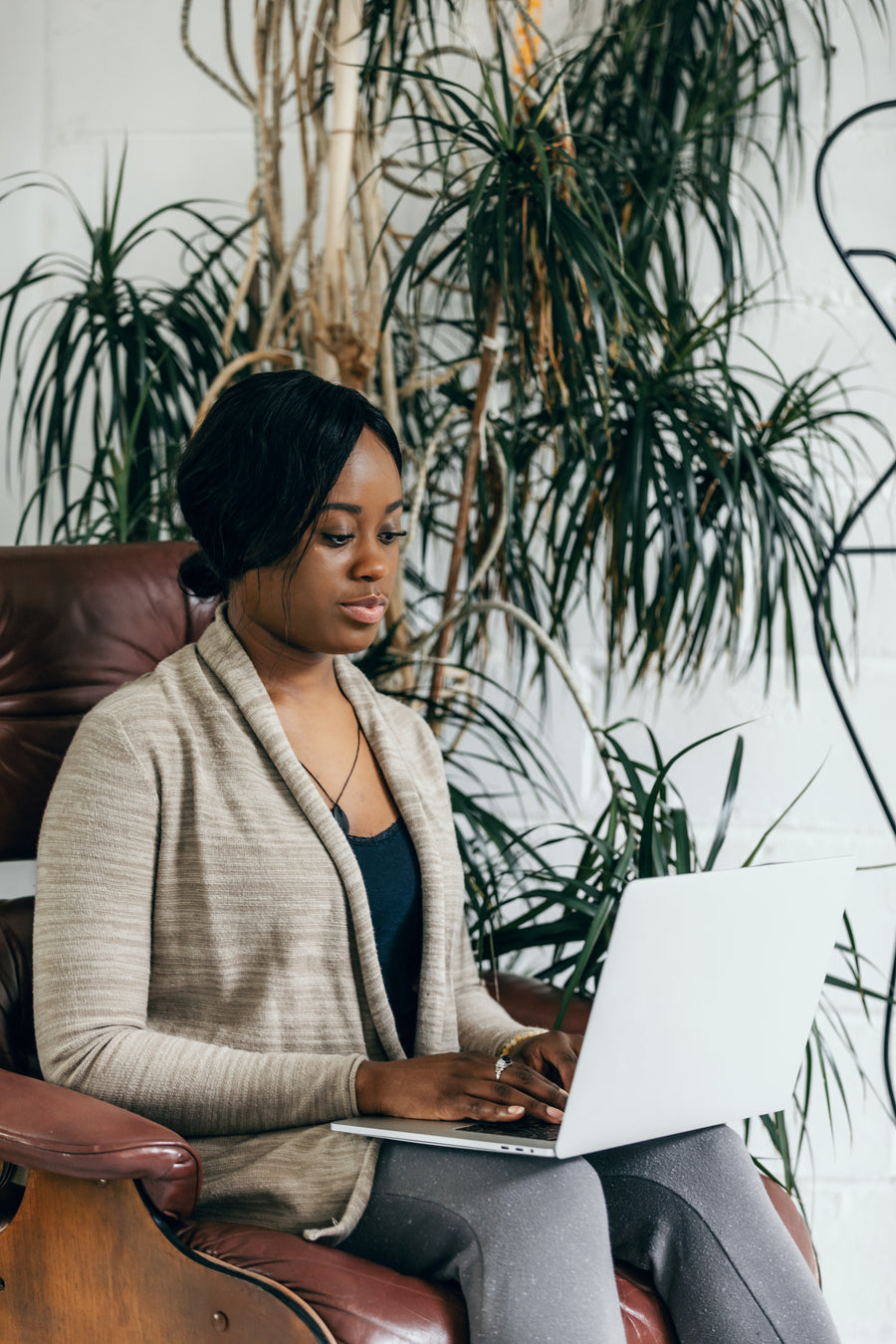 Person working on a laptop surrounded by indoor plants
